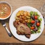 The finished Clamper feast: New York steak, spicy beans, potatoes, fresh salad, and a glass of moonshine