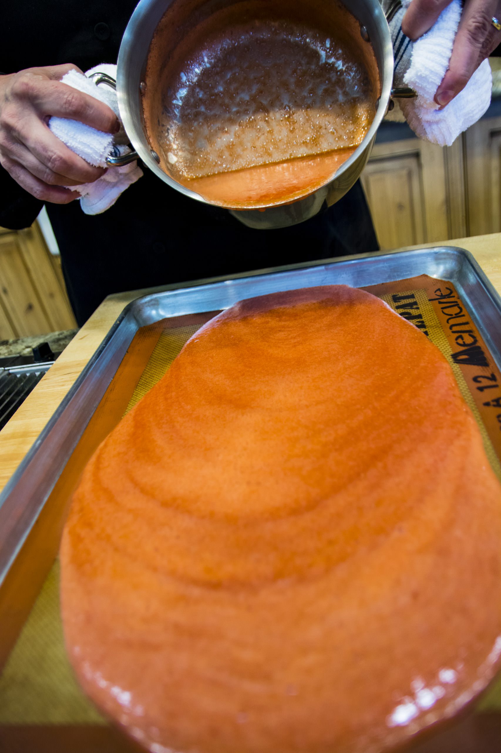 Fruit leather Pouring puree onto covered baking sheet to dry in oven03
