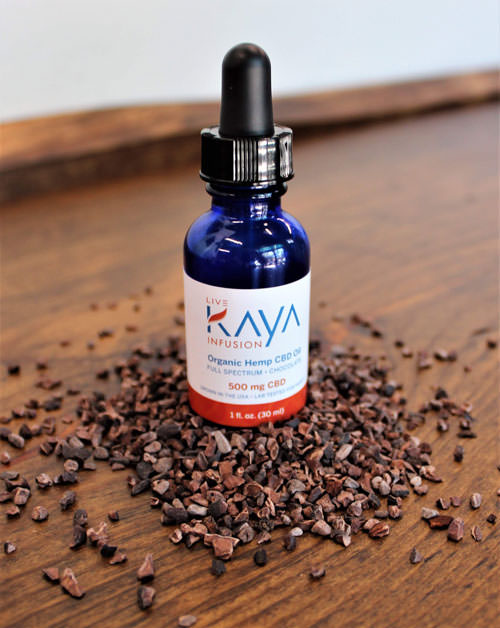 bottle of organic CBD hemp oil infusion from LiveKAYA surrounded by cacao nibs