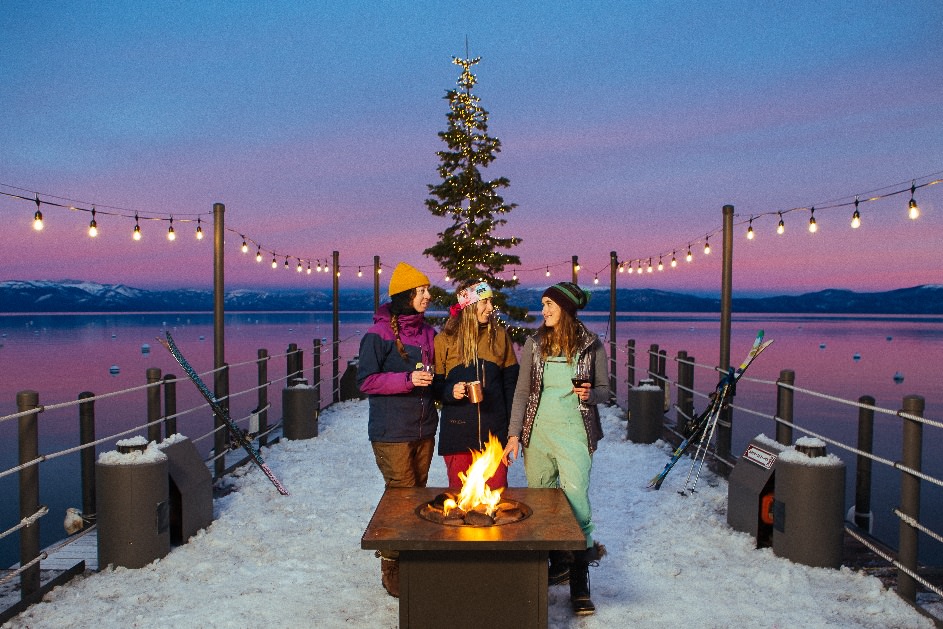 People enjoying s'mores by a firepit on a pier