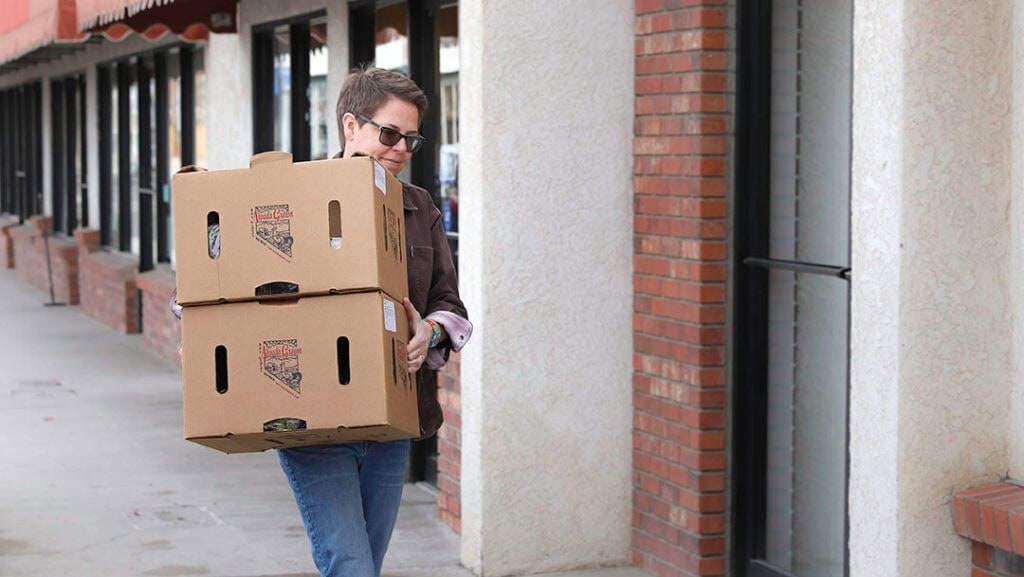Fallon Food Hub Executive Director Kelli Kelly carries CSA boxes for distribution in downtown Fallon. Photo by Shaun Hunter