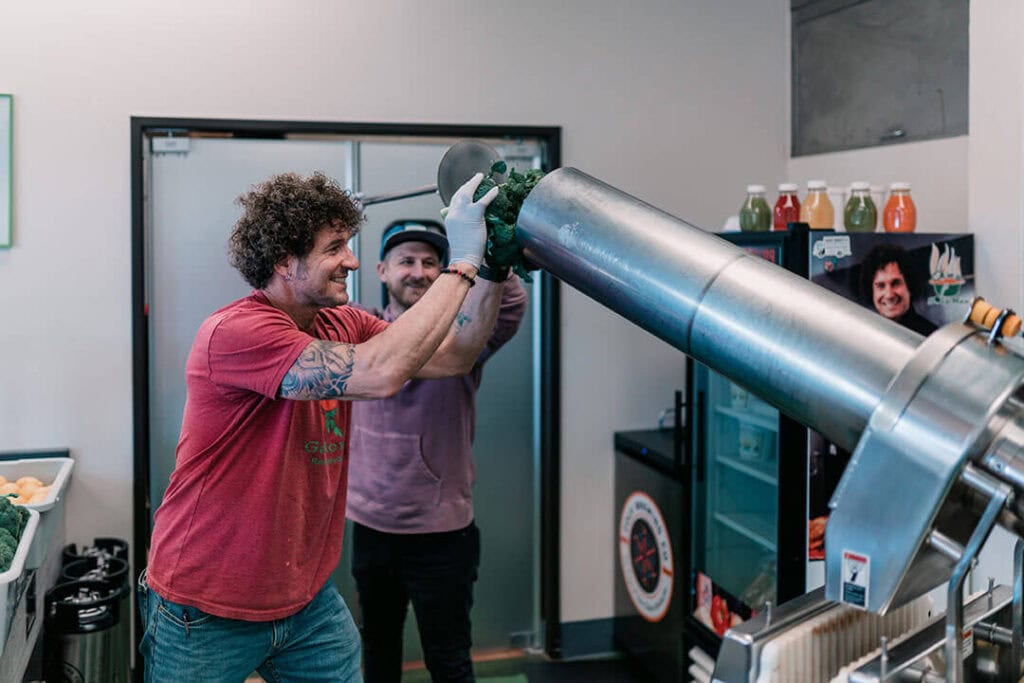 From left, Gino Scala, Great Full Gardens co-owner, and Wilson Wood, Great Full Gardens marketing manager, load produce into the juicer