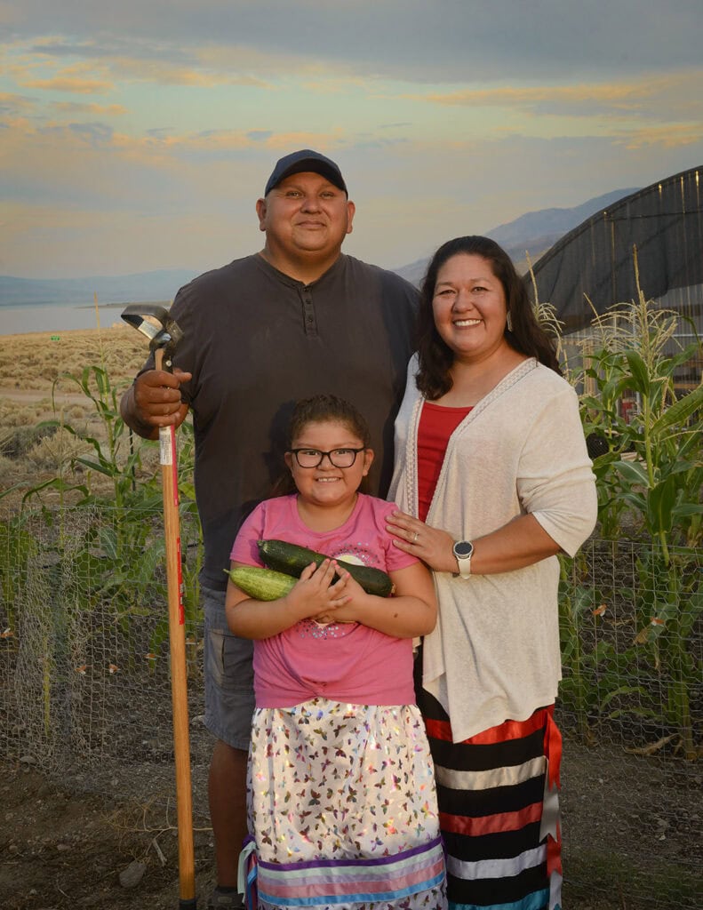 Loren Decker with his wife, Melissa, and their granddaughter, Priseis Decker, in front of the garden and hoop house on their property in Sutcliffe near Pyramid Lake, on the Paiute Tribeโs reservation.