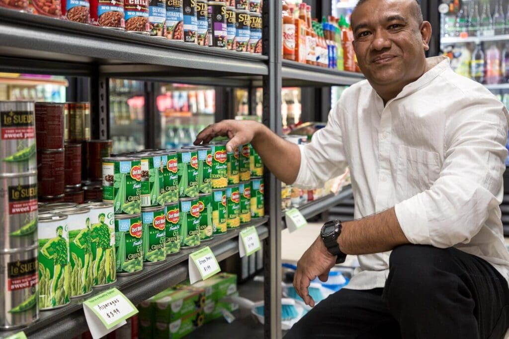 Vassar Market owner Hachib Hossain proudly stacks canned vegetables