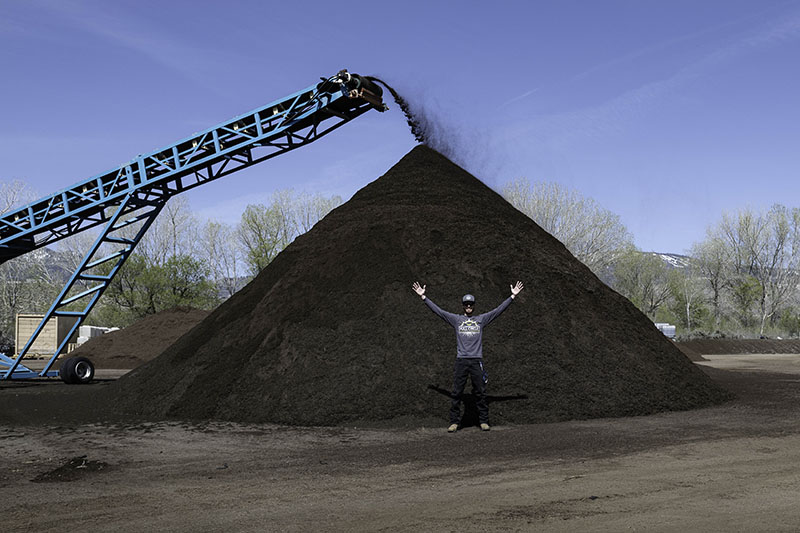 Cody Witt stands in front of a pile of compost at Minden’s Full Circle, which is being filtered to remove large debris. This is the last step before the compost is bagged. Photo by Mary Claire Bouchér