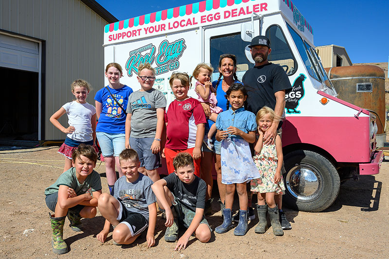 Cheryl and Kenny Wright stand with their after-school program students and three of their daughters, who all participate in managing animals at Kool Kids Ranch. They sell eggs, ice cream, and dog treats out of the converted mail truck