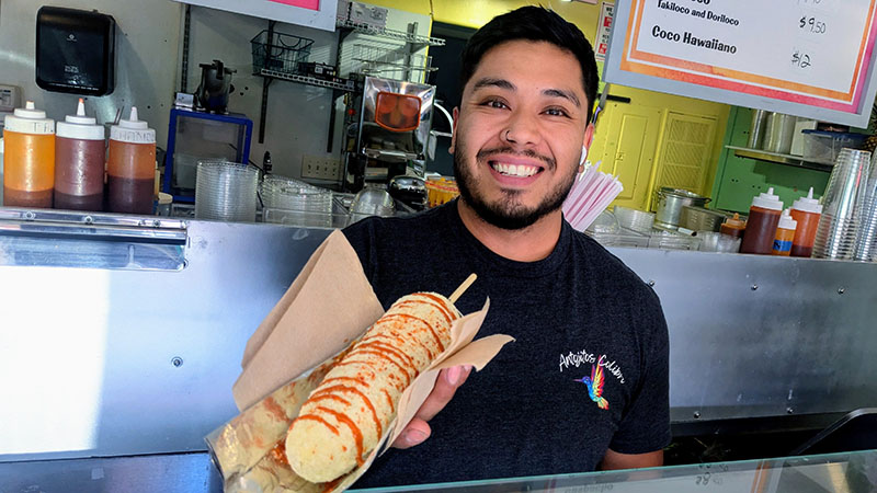 Mauricio Muñoz, son of the owners of Antojito Colibrí, serves elote to families who say the snack reminds them of their homelands