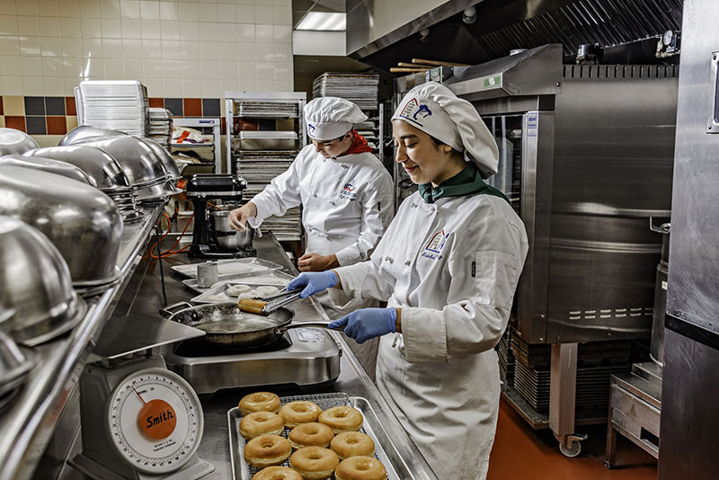 From left, Kyle Moyer and Laisha Sanchez, students in the culinary program at AACT in Reno, prepare baked goods in the kitchen. Photo by Donna Victor