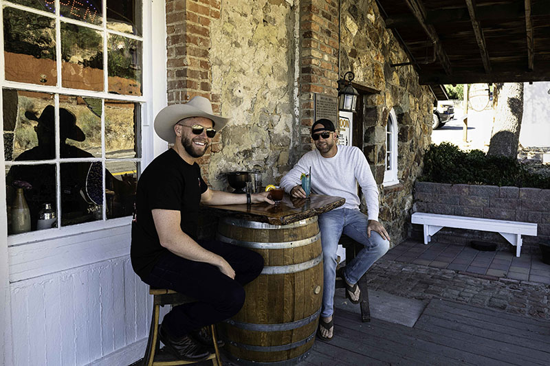 Crown Point Restaurant patrons Ethan and Jake Wilson enjoy cocktails at the new barrel-and-Tahoe-pine bar tables on the porch, paid for by the grant the restaurant received. Photo by Mary Claire Bouchér