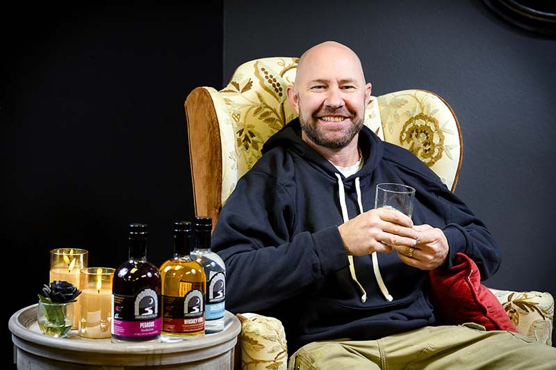 Robbie Anderson, founder and master distiller at Underworld Distillery, poses in his Victorian-gothic-themed bar in an industrial park in South Reno. Photo by Mike Higdon