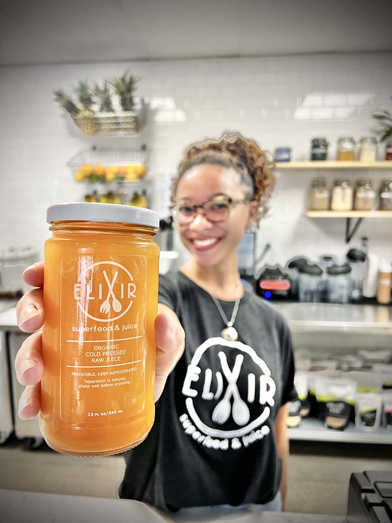 Elixir employee Asia McCoy presents one of the store’s cold-pressed juices made fresh daily