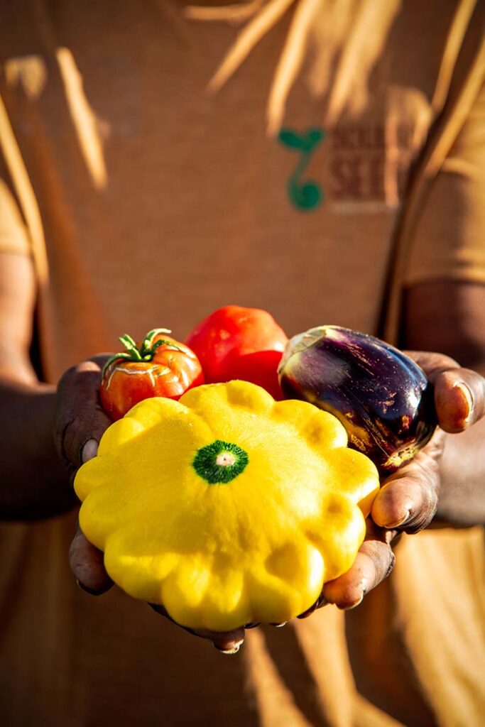 Earstin Whitten holds tromboncino squash, eggplant, and tomatoes grown at Soulful Seeds