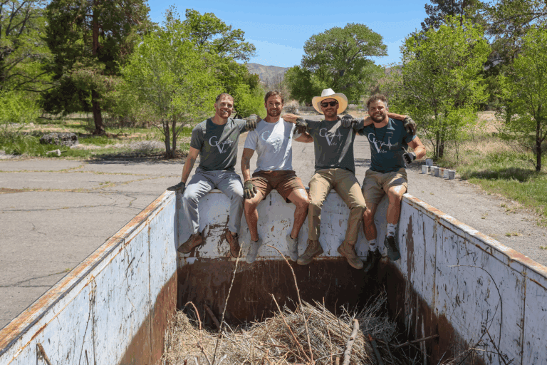 From left, GreenVibe World members Zachary Smith, Walker Sauls, Andrew Sauls, and Sinjen Smith sit on a dumpster filled with brush following a Truckee River area cleanup