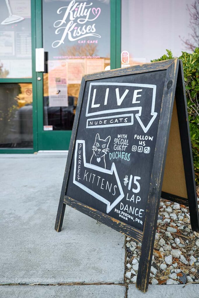 A playful sign at the cafรฉโs entrance compels guests to stop in