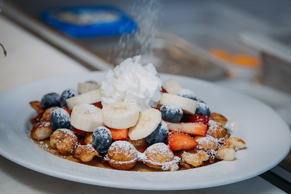 Honey comb waffle topped with honey, maple syrup, fresh fruit, and whipped cream