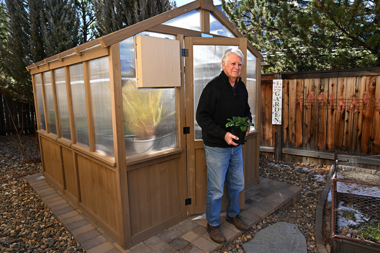 Ken Gerhart stands in front of his own greenhouse