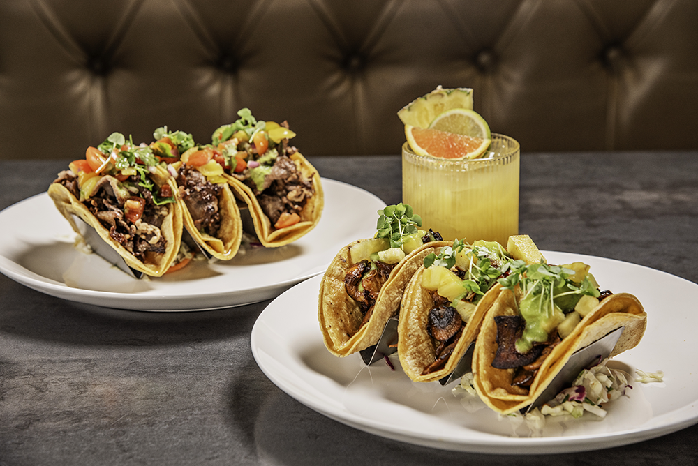 Black Angus rib eye tacos (left), a don't tell me what to do signature cocktail, and exotic mushrooms al pastor tacos (right)